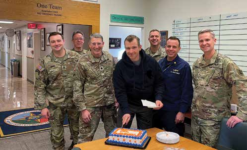Team CLAMO celebrates the birthday of its German exchange officer, Dr. Ganschow, who is cutting the
        cake. (Photo courtesy of authors)